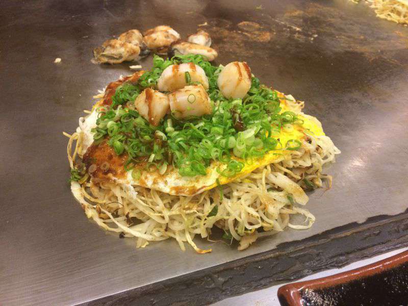 Photograph of Okonomiyaki in Hiroshima, made with cabbage, noodles, scallops and lots of other things!