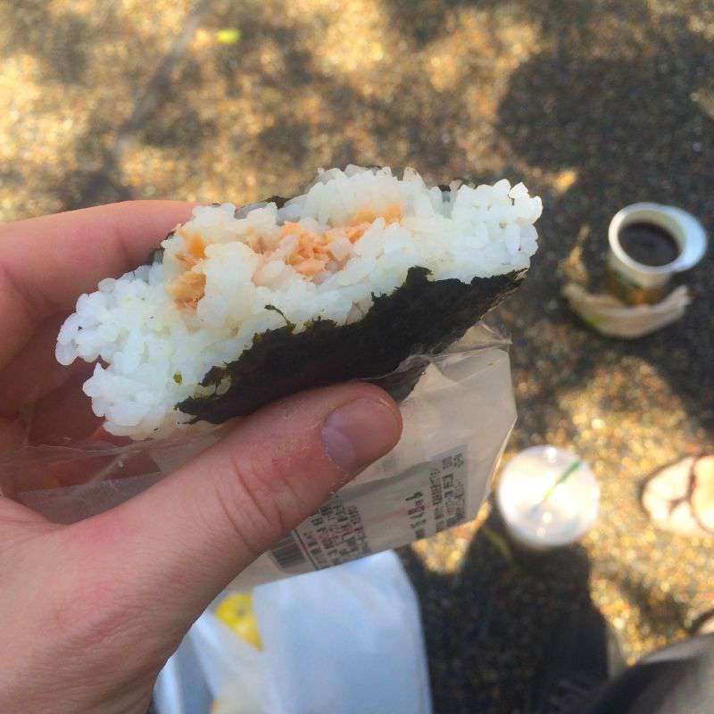 Photograph of Lunch on the go in Tokyo, eating salmon onigiri wrapped in nori
